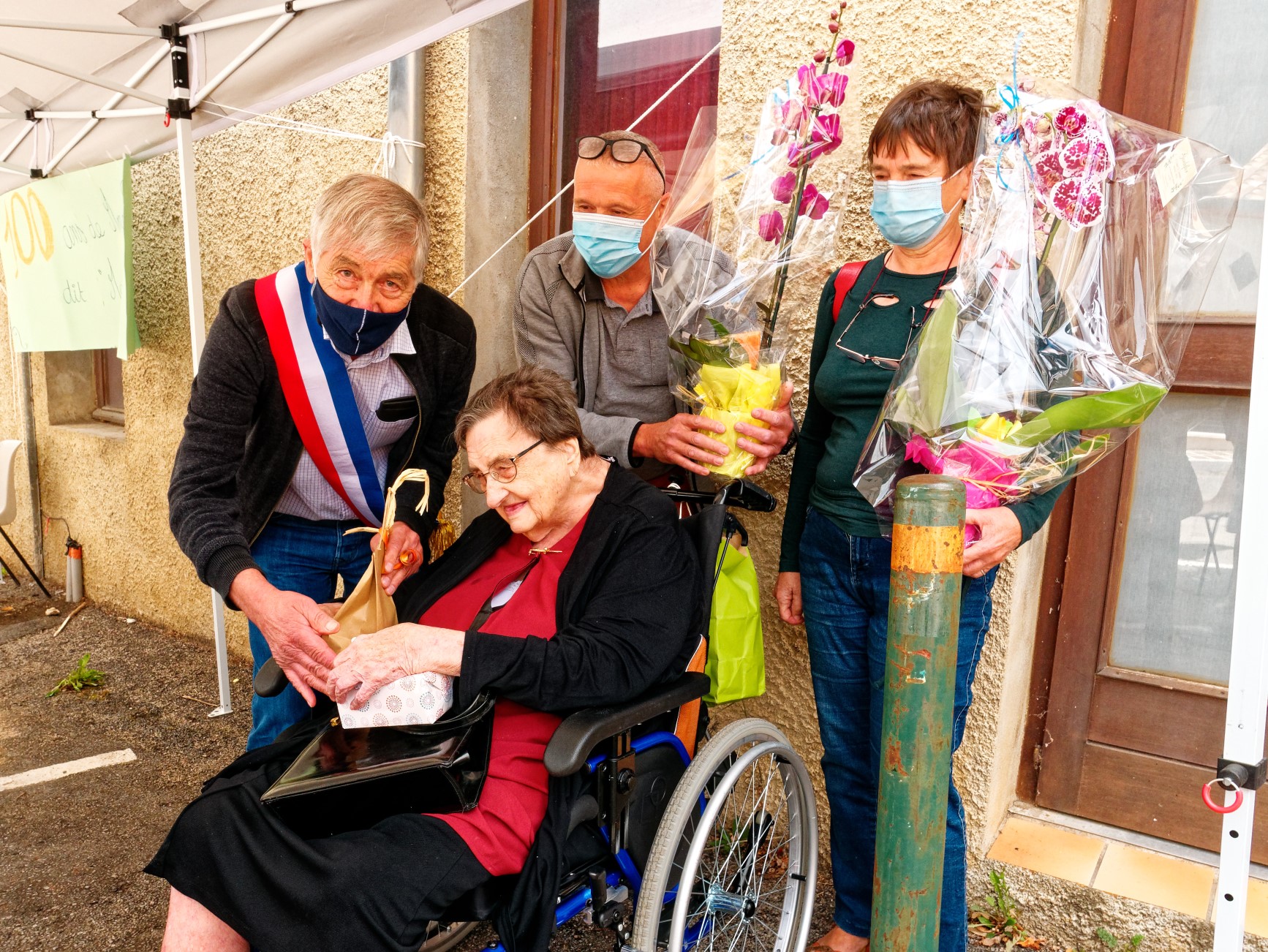 Alain DURAND et deux adjoints remettent des bouquets de fleurs et des friandises à "Marraine"